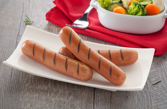 Tres Franks Original de pollo en un plato blanco, con guarnición de verduras